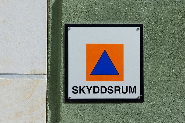 Skylt där det står Skyddsrum, blå triangel i en orange kvadrat