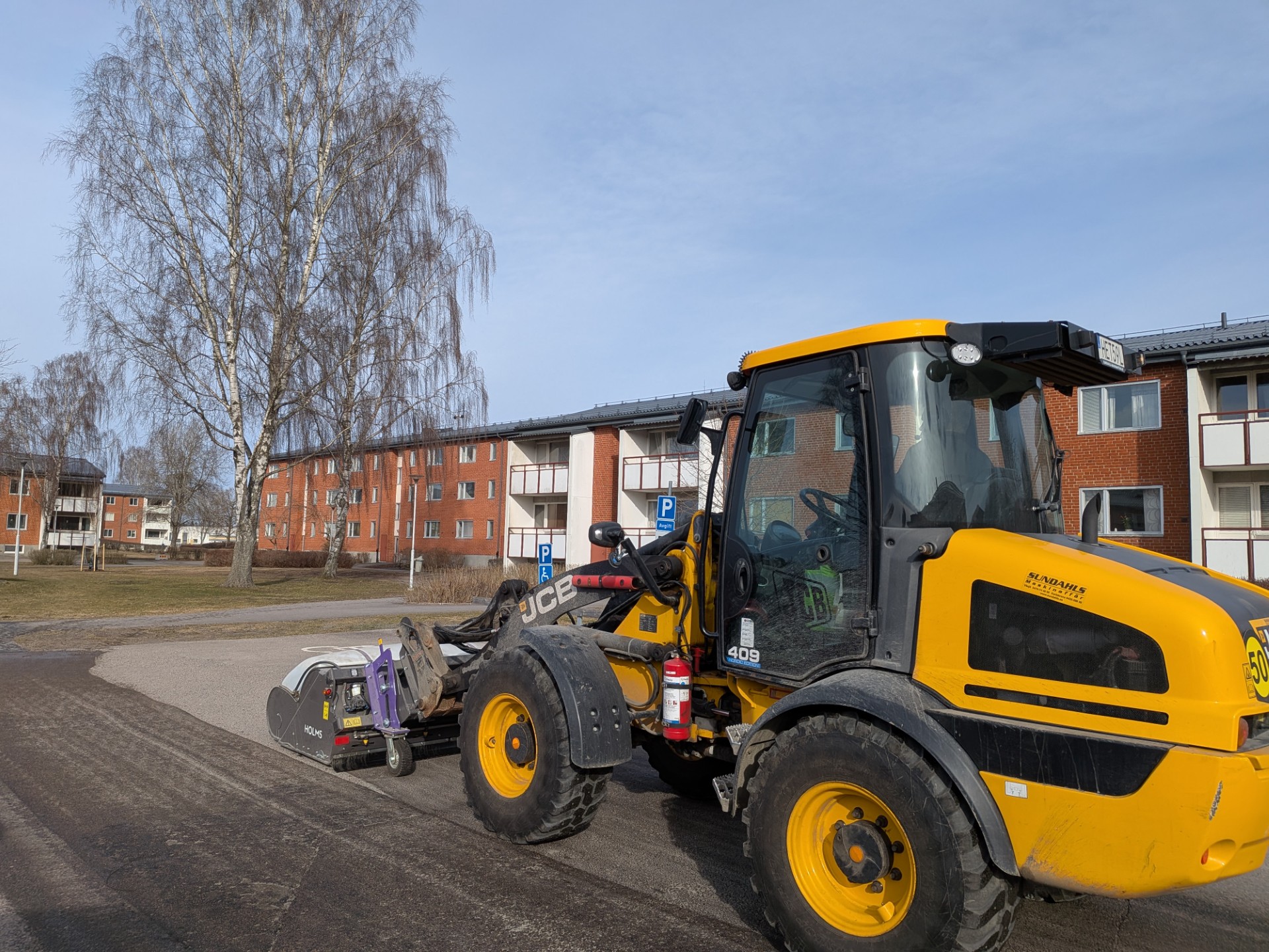 En maskin som sopar upp grus i ett kvarter