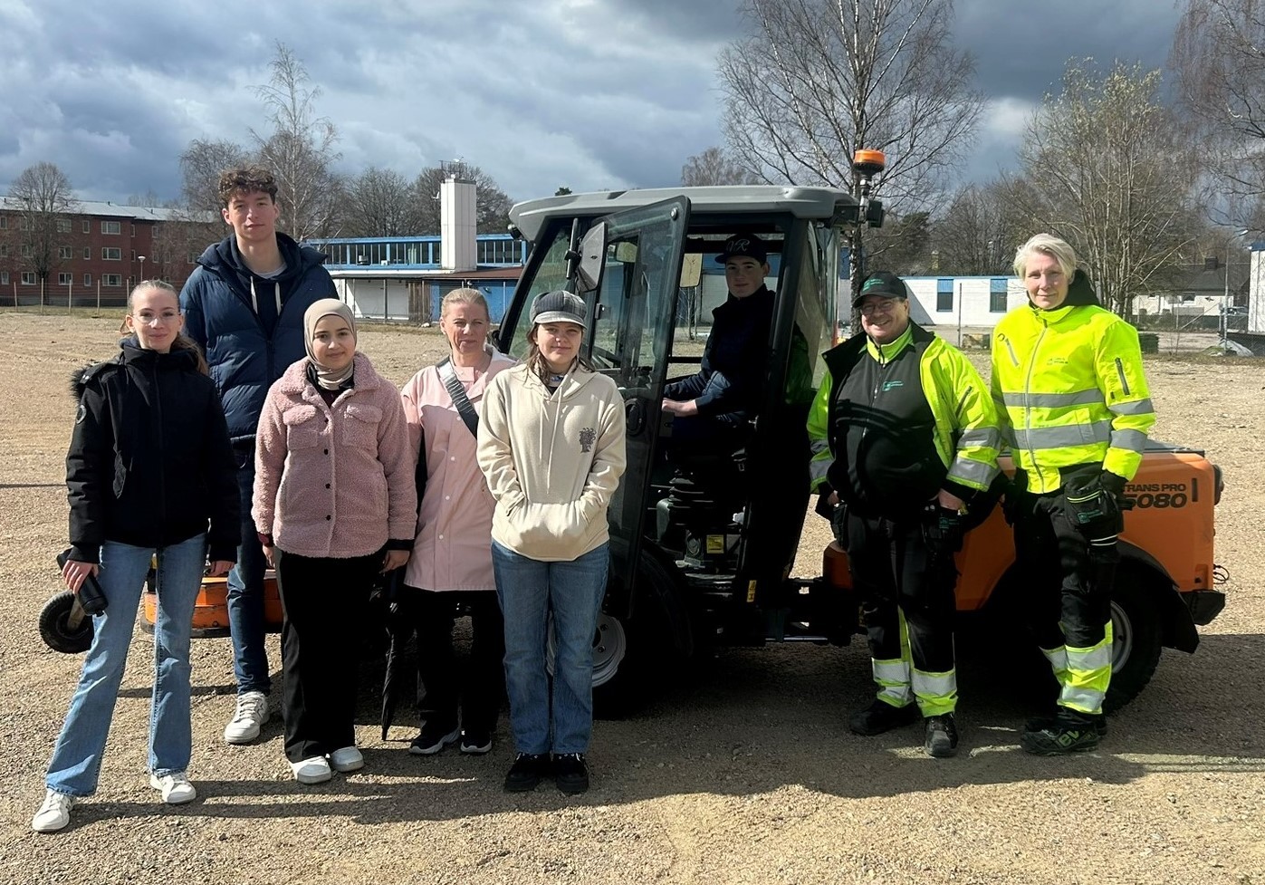 En grupp elever framför en åkgräsklippare